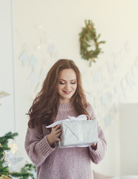 クリスマスのギフトボックスを保持しているスマイリーの女性