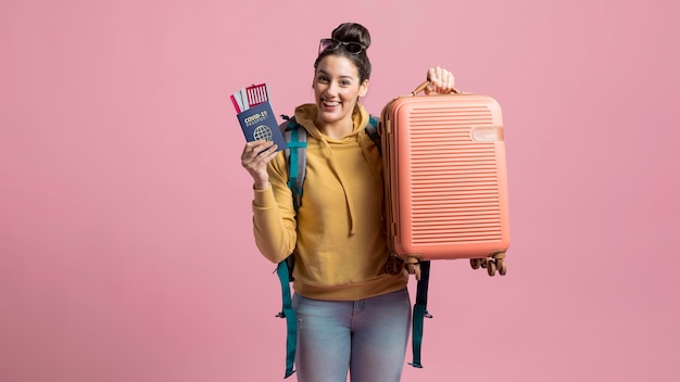 Smiley woman holding health passport and luggage