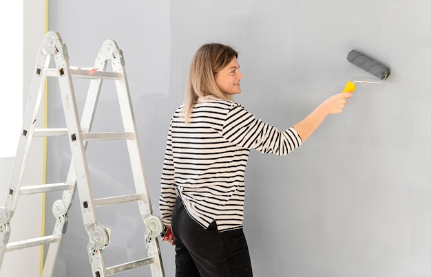 Photo smiley woman painting wall medium shot