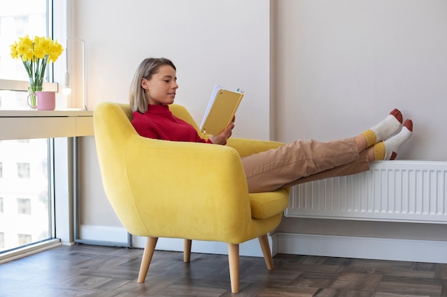 Smiley woman reading at home full shot