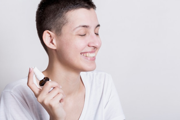 Smiley woman spraying face care product