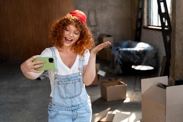 Photo smiley woman taking selfie with smartphone in her new home