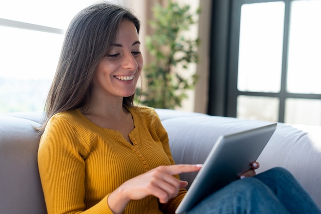 Photo smiley woman using tablet on the sofa