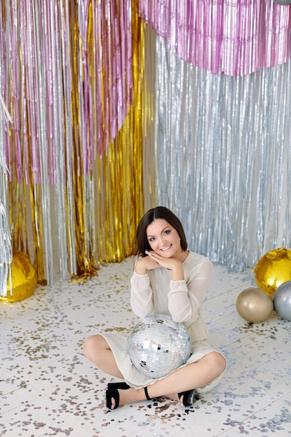 Smiley woman with a disco ball on a Christmas party. Christmas decorations disco party style.