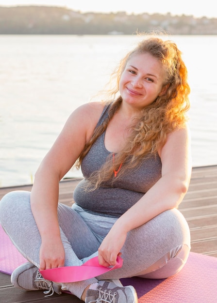 Foto donna sorridente con elastico in riva al lago