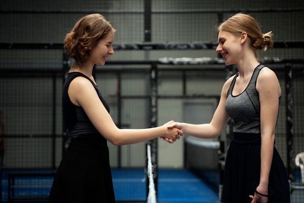 Foto donne sorridenti che stringono la mano vista laterale