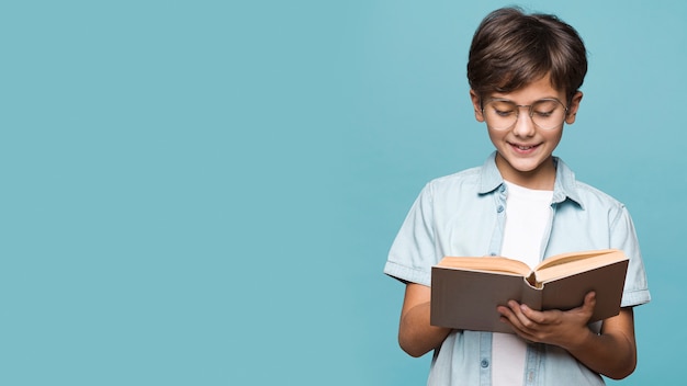 Photo smiley young boy reading book