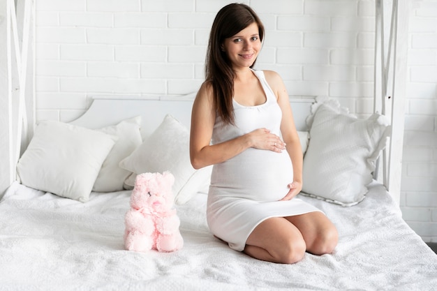 Foto smiley zwangere vrouw die haar baby voelt