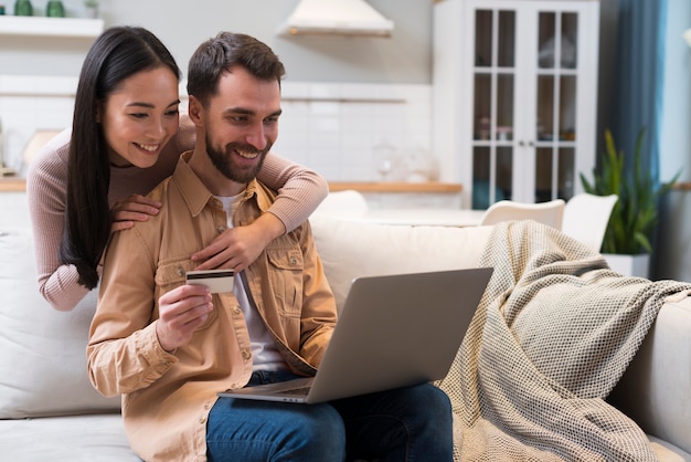 Foto smileypaar met creditcard en laptop die online winkelen