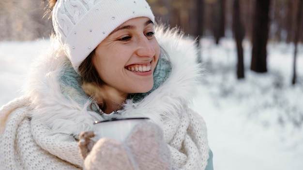 Smileyvrouw buiten in de winter met een kopje thee