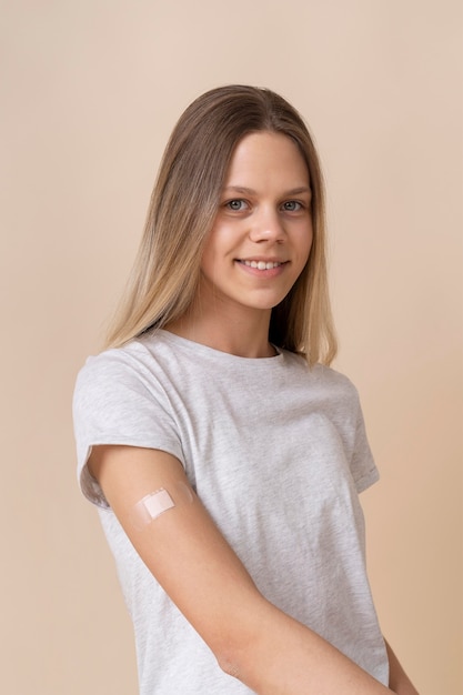 Smileyvrouw die arm met sticker toont na het krijgen van een vaccin