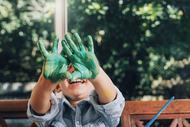 写真 笑顔の少年が顔の上に汚れた手を見せている