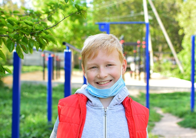 写真 通りで微笑んでいる9歳の男の子は彼の医療マスクを脱いだ