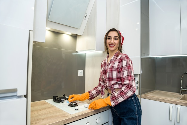 Smiling adult girl cleaning kitchen with spray bottle and a microfiber cloth