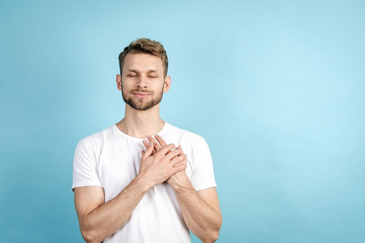 Smiling adult guy holding hands on chest