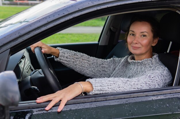 車を運転して笑顔の大人の女性