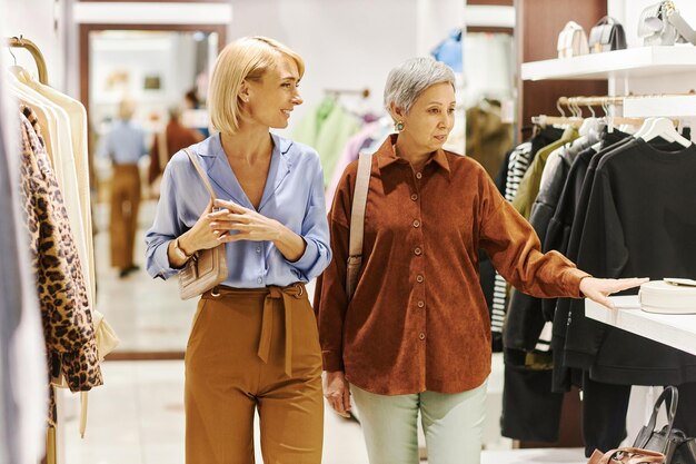 Smiling adult woman with mother shopping together in clothing boutique