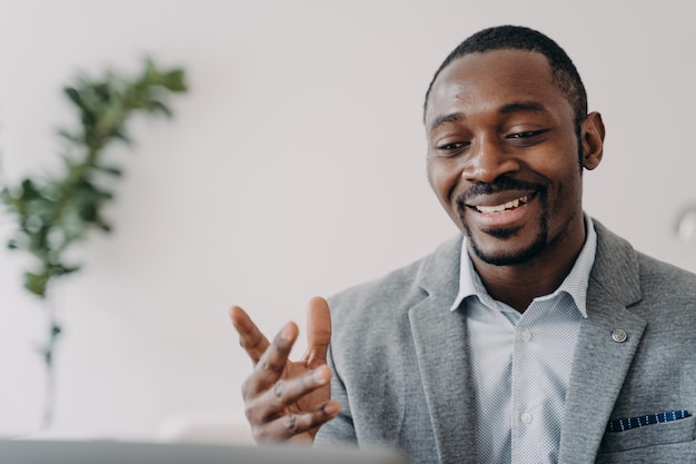 Smiling african american businessman holding a video call with customers on laptop advises clients