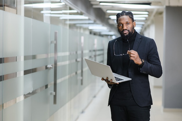 Smiling african american businessman standing alone in a large office high quality photo