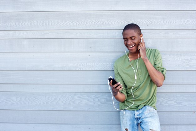 イヤホンで音楽を聴いているアフリカのアメリカ人男性を笑って