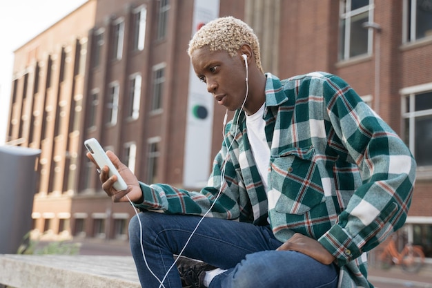 Smiling African American man holding mobile phone reading text message, communication online