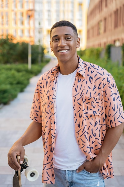 Smiling African American man holding skateboard looking at camera