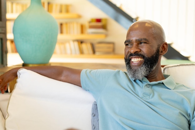 smiling african american man relaxing on couch at home enjoying leisure time