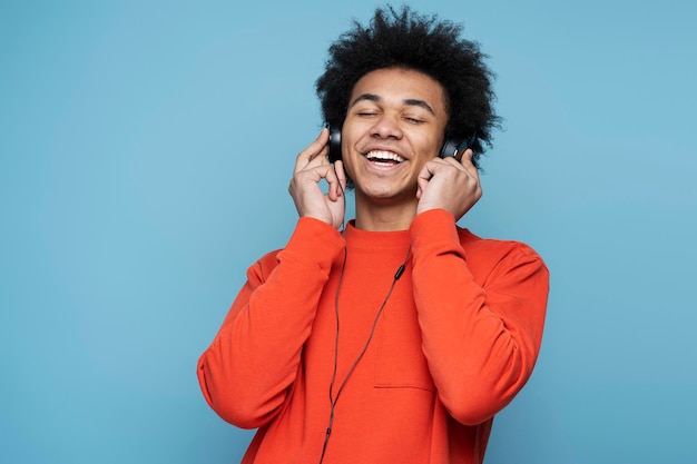 Smiling African American man wearing headphones listening music isolated on blue background