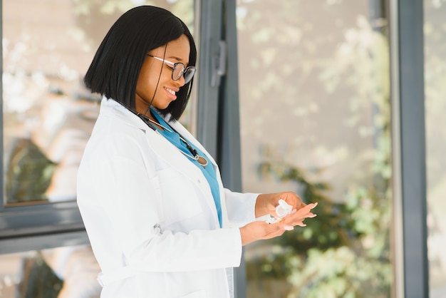 Smiling african american nurse with stethoscope holding pill