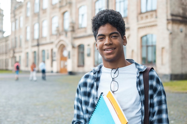 Smiling African American student in glasses with books. 