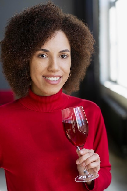 ホーム パーティーで赤ワインのお祝いの誕生日のガラスを保持している笑顔のアフリカ系アメリカ人女性