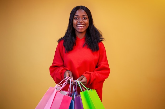 カメラを見ているカラフルなバッグと赤いパーカーで笑顔のアフリカ系アメリカ人女性