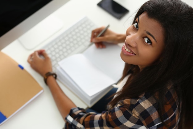 Smiling african american woman takes notes and writes in notebook