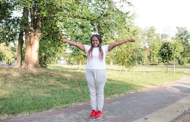 Smiling African-American woman training with a rope in the open air