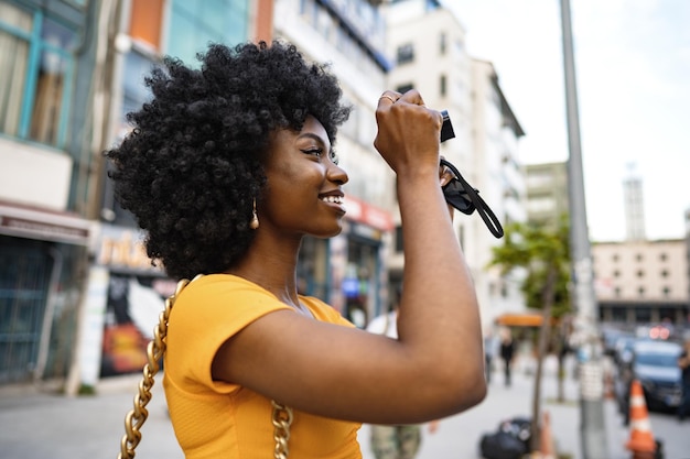 Photo smiling african american woman using professional camera at a street