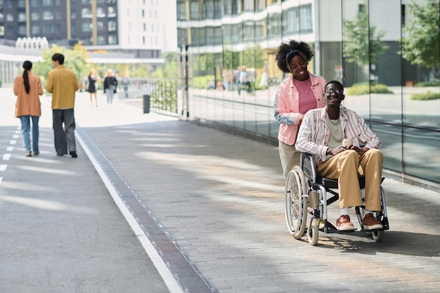 Smiling African American woman walking with her friend with disability in the city