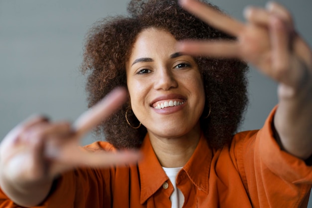 Foto sorridente giovane donna afroamericana sorridente che mostra segni di pace con le dita