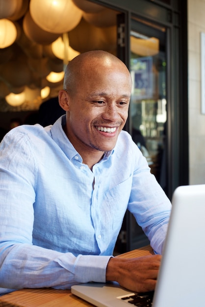 Uomo d'affari africano sorridente che lavora al computer portatile