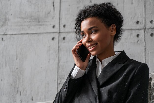 smiling african businesswoman in armchair on phone