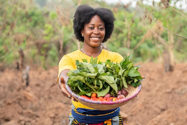 Smiling african farmer carrying a basket of vegetables