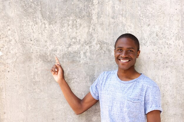 smiling african man in blue t-shirt pointing at copy space