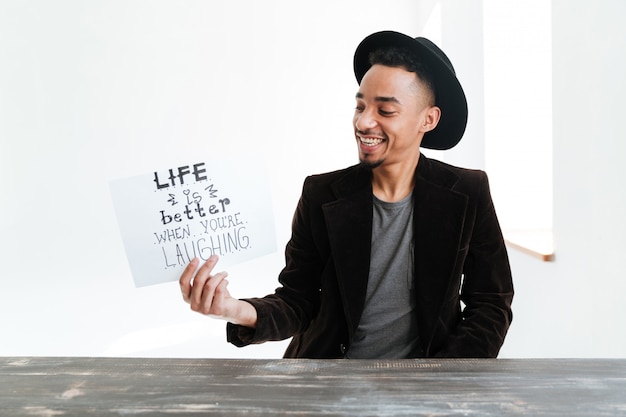 Smiling African man holding sheet of paper with words