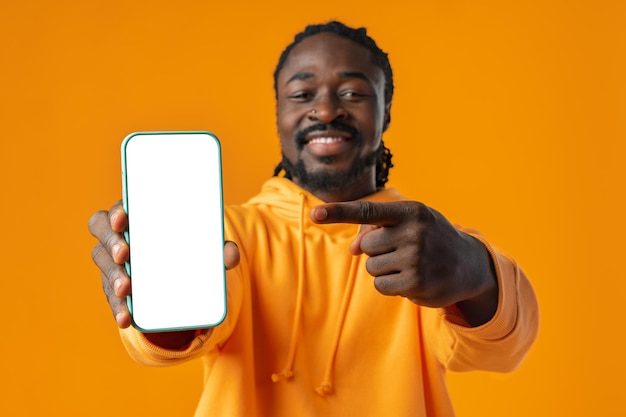 Smiling african man pointing at cellphone with blank screen with copy space