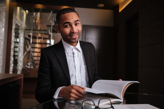 Smiling african man in suit sitting with journal