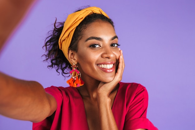 Sorridente donna africana in abito che fa selfie