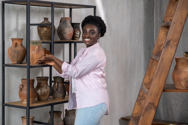 Donna africana sorridente in abiti rosa nello studio di ceramica