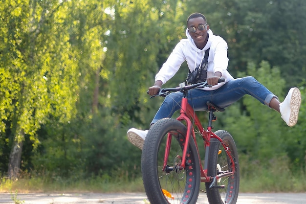 Un uomo afroamericano sorridente va in bicicletta nel parco uno stile di vita attivo