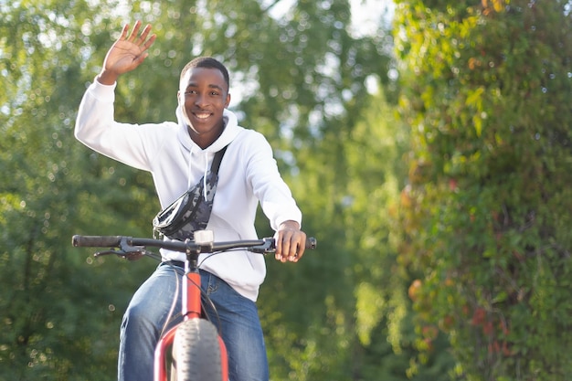 A smiling AfricanAmerican man rides a bicycle in the park An active lifestyle