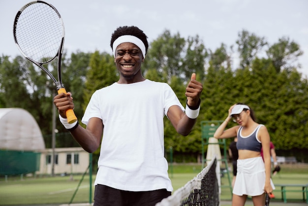 Smiling africanlooking tennis player won match against young athlete he holds the racket