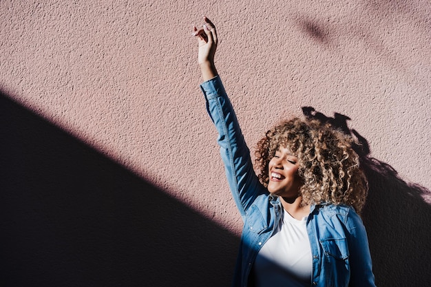 Smiling afro hispanic woman in sunny day with eyes closed enjoying outdoors city lifestylespring